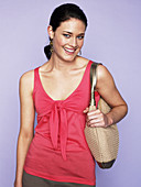 A brunette woman wearing a red top with a bag over her shoulder