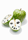 Cherimoya, whole and halved against a white background