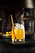 Yellow cocktail in a glass with cinnamon and orange
