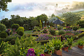 Blick von oben auf Hanggarten mit Pavillon und Beet mit Rosenstämmchen, eingefasst mit Buchshecke