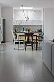 Dining area with various chairs in front of white painted brick wall in open plan living room