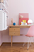 Desk with classic chair and shelves in girl's bedroom with pink wallpaper