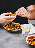 Man eating fried potato wedges with barbecue sauce