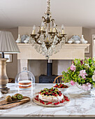 Kiwi and berry cake on marble countertop below French chandelier