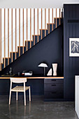 Schreibtisch mit Stuhl an schwarz gestrichener Treppenwand
