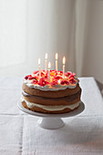 Naked Cake als Geburtstagskuchen dekoriert mit Kerzen und Blüten