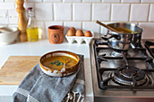 Cremesuppe in Keramikschale neben Gasherd in Landhausküche
