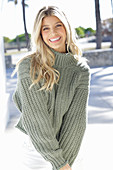 A young blonde woman wearing a grey knitted jumper