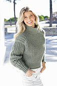 Junge blonde Frau in grauem Strickpullover