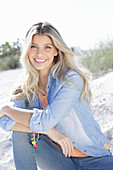 A young blonde woman wearing denim and an apricot top