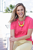 A young blonde woman wearing a pink t-shirt and a pair of light trousers