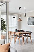 Various lamps above dining table and wooden upholstered chairs