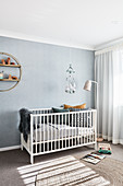 Cot against pale blue wall in minimalist nursery