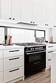Gas cooker in classic, white kitchen with horizontal window