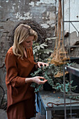 Woman looking at plant in greenhouse
