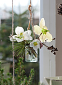 Kleiner Strauß aus Christrosen, Kiefernzweig, Haselzweig und getrocknetem Hortensienzweig in Glas ans Fenster gehängt