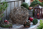 Ball of clematis vines with fairy lights, Christmas tree ornaments, moss wreath, and a lantern, lightly dusted with snow