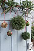 Christmas tree ornaments in a forest motif: glued with pine needles, fir branches, fern leaves, and autumn leaves on a spruce branch