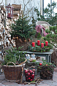 Christmas terrace with Christmas tree, Advent wreath, baskets with fir branches, pinecones, and Christmas tree decorations, a mug with a hot mulled cider on wooden disc, antlers, and old wooden skates as decoration