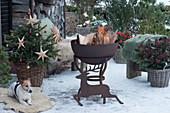 Verschneite, weihnachtliche Terrasse mit Feuerschale und Weihnachtsbaum, Hirschsilhouette aus Edelrost, Hund Zula liegt auf Fell