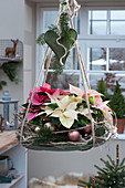 Hanging Christmas decoration with a wreath of twigs, poinsettias, Christmas tree ornaments, heart, and fir branches