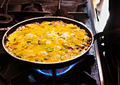 Preparing fritatta in a pan on a gas stove