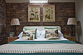 Double bed below botanical drawings on rustic board wall in bedroom