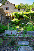 Sommerlicher Garten und Natursteinhaus in Hanglage