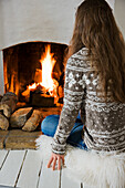 Woman wearing Norwegian jumper sitting in front of the fireplace