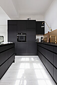 Modern black kitchen with white floorboards