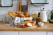 Brotkorb, Oliven und Weißwein auf Küchenarbeitsplatte