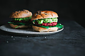 Vegetarian bagel burger with red beet patty and avocado