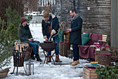 Friends roasting chestnuts in an iron pan on the grill