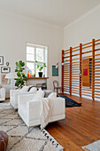 White leather armchairs in front of wall racks in an open-plan living room