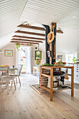 Open-plan interior with wooden floorboards and white-painted wooden ceiling, kitchen shelve in the foreground