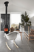 Christmas atmosphere with modern rocking chair, fireplace, and spruce branch in open living room