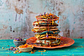 Naturally coloured pancakes served with edible flowers and syrup