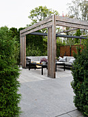 Black tables and outdoor sofas below wooden pergola