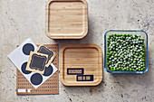 Frozen peas in glass storage containers with wooden lids