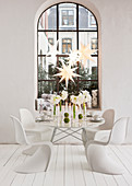 Table decorated for Christmas with amaryllis and white classic chairs