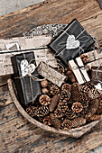 Various conifer cones and wrapped gifts in wooden bowl on rustic wooden table