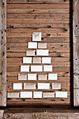 Envelopes arranged in shape of Christmas tree on rustic board wall