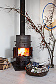 Lit fire in wood-burning stove, Christmas presents and larch branches