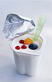 A mug of yogurt with a spoon and berries