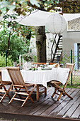 Set table with white tablecloth and chairs on a wooden patio