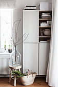 Cherry branches in glass demijohn on wooden stool