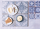Hummus mit Crackern serviert auf blau-grauen Musterfliesen