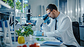 Scientist in safety glasses analyzing a lab-grown tomato