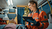 Paramedic using tablet computer in ambulance
