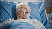 Man wearing oxygen mask in hospital bed